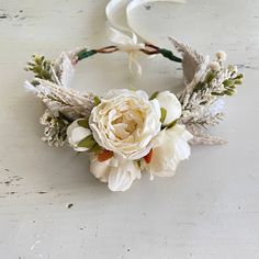 a white flower headband with feathers and flowers on the side, sitting on a table