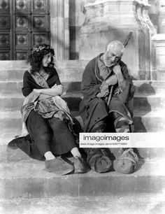 an old black and white photo of two people sitting on steps with their arms around each other