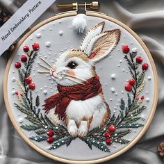 a white and brown rabbit in a wreath with red berries