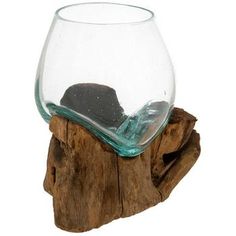 a glass with some rocks in it sitting on top of a piece of driftwood