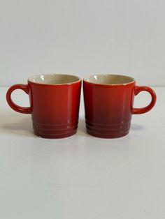 two red mugs sitting next to each other on a table