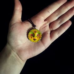 a person's hand holding a yellow and green pendant