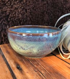 a blue bowl sitting on top of a wooden table next to a pile of wires