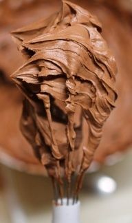 a whisk filled with chocolate frosting on top of a counter