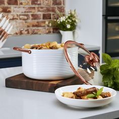 a white bowl filled with food sitting on top of a counter next to a plate