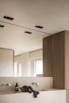 a bathroom with two sinks and mirrors in the wall, along with lights on the ceiling