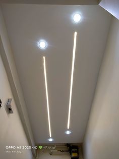 two lights are on the ceiling in an empty room with white walls and flooring