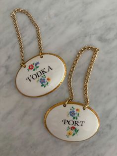 two white and gold necklaces with the words vodka, port written on each one