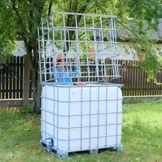 a man sitting in a metal cage on top of a grass covered field next to a tree