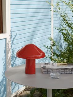 a red mushroom lamp sitting on top of a white table next to a blue house