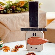 a snowman made out of wood sitting on top of a table next to orange slices