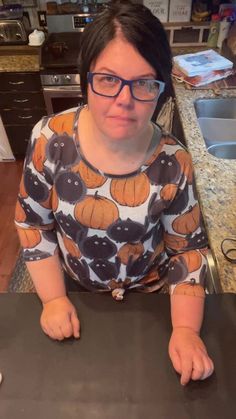 a woman wearing glasses sitting at a kitchen counter