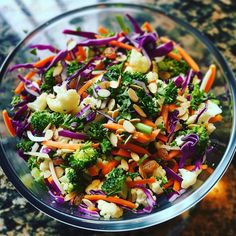 a glass bowl filled with broccoli, cauliflower, carrots and other veggies