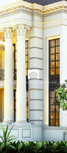 a large white building with columns on the front and second story, surrounded by greenery