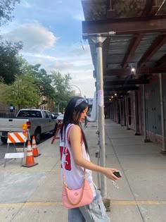 a woman standing next to a pole holding a cell phone