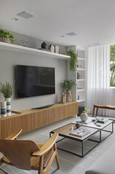 a living room filled with furniture and a flat screen tv mounted on a wall next to a window