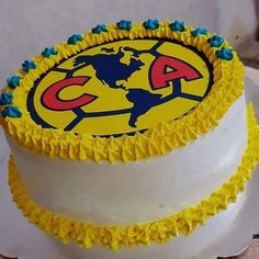 a three layer cake with yellow icing and blue decorations