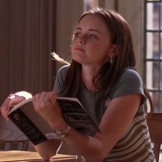 a woman sitting at a table reading a book