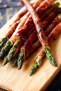 asparagus wrapped in bacon on a cutting board