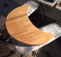 a wooden table sitting on top of a metal cart next to a white and black chair