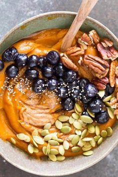 a bowl filled with carrots, blueberries and nuts