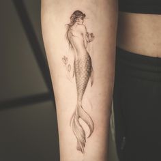 a woman's arm with a mermaid tattoo on the left side of her body