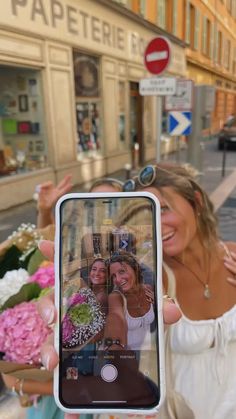 a woman taking a selfie with her cell phone in front of a flower shop