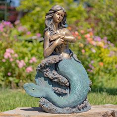 a statue of a mermaid sitting on top of a rock