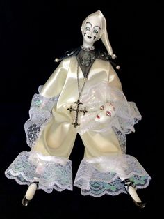 a white doll with black hair wearing a cross and laces on it's legs