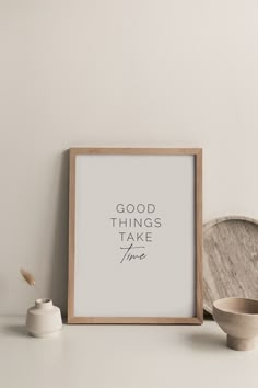 a wooden frame sitting on top of a white table next to a bowl and cup