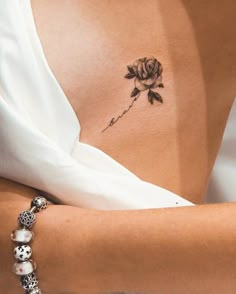 a woman's arm with a rose tattoo on the back of her left shoulder