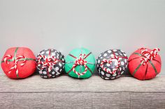 four balls wrapped in red and green paper with bows are sitting on a couch next to each other