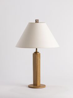 a table lamp with a white shade on it's base and a gold finish