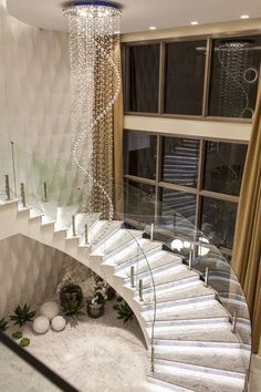 a spiral staircase with chandelier hanging from it's sides in front of a window