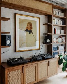 a living room with bookshelves, speakers and a painting on the wall above it