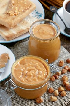 peanut butter and toast on a table with coffee, spoons and plates full of peanut butter