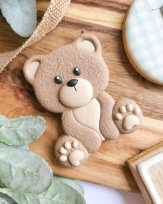 a cookie shaped like a teddy bear sitting on top of a cutting board next to a plant