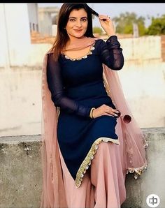 a woman in a blue and pink outfit posing for the camera with her hand on her head