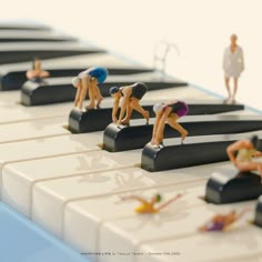 figurines are sitting on the keys of a piano