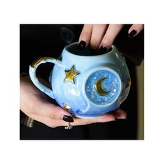 a woman's hand holding a blue coffee mug with gold stars and moon on it