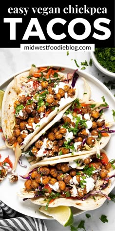 three tacos on a plate with limes and cilantro