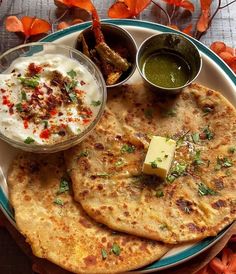 two flatbreads on a plate with dip and vegetables