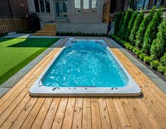 a hot tub sitting on top of a wooden deck next to a lush green yard