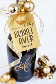 a bottle of bubble over with gold ornaments around it and a tag that says, may your birthdays bubble over with joy