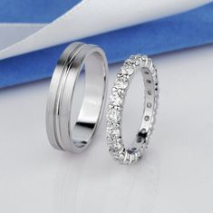 two wedding rings sitting next to each other on top of a blue and white cloth