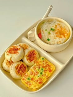 an egg omelet and soup are on a white plate with chopsticks