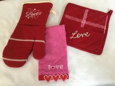 three red oven mitts and one pink oven mitt with love written on them