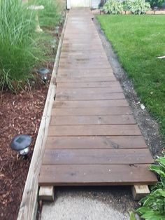 a wooden walkway in the middle of a garden