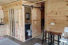 the inside of a small cabin with wooden walls and flooring, including two stools