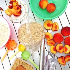 a table topped with plates and bowls filled with food next to peaches, oatmeal bars and other fruit